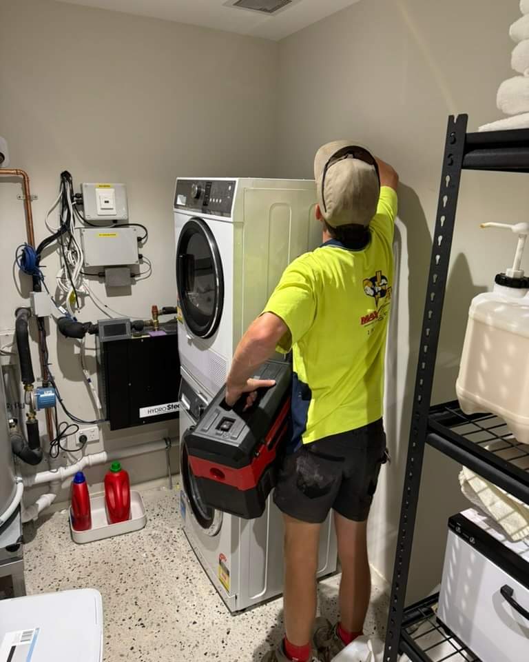 A man wearing a yellow shirt is positioned next to a washing machine, highlighting domestic chores.