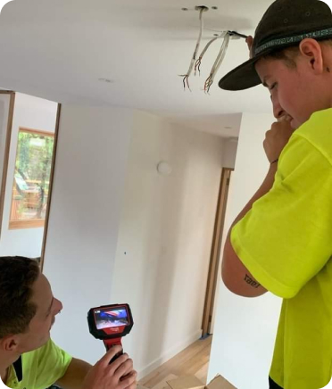 Two men wearing green shirts are engaged in work on a ceiling