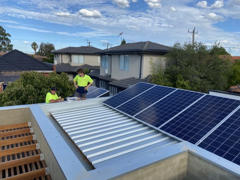 Two men installing solar panels on a roof